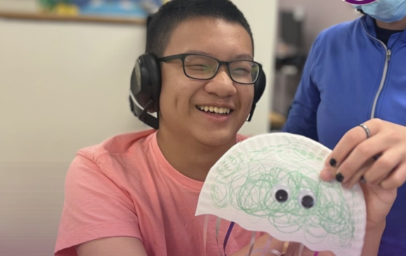 Teenage RCS Learning Center student smiling and holding up a craft